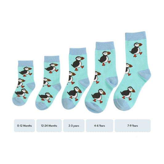 Set of children's socks with puffin design on a light blue background, with size labels below.