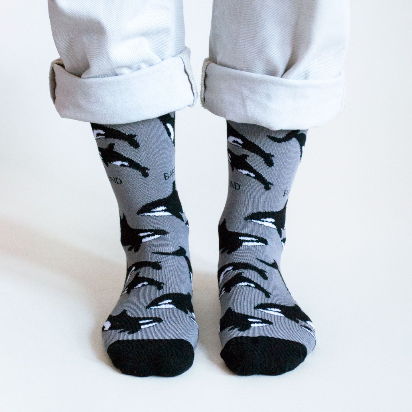 standing model wearing black bamboo socks with an orca design