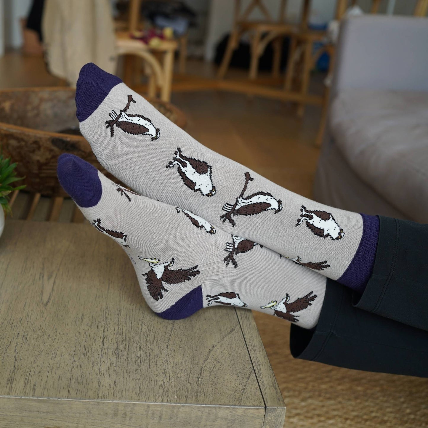 Person wearing Osprey bamboo socks on a wooden surface in a room setting
