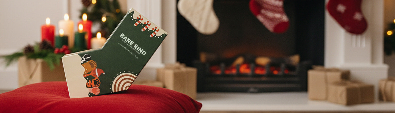 Bare Kind christmas gift box on a red surface in front of a fireplace with Christmas decorations.