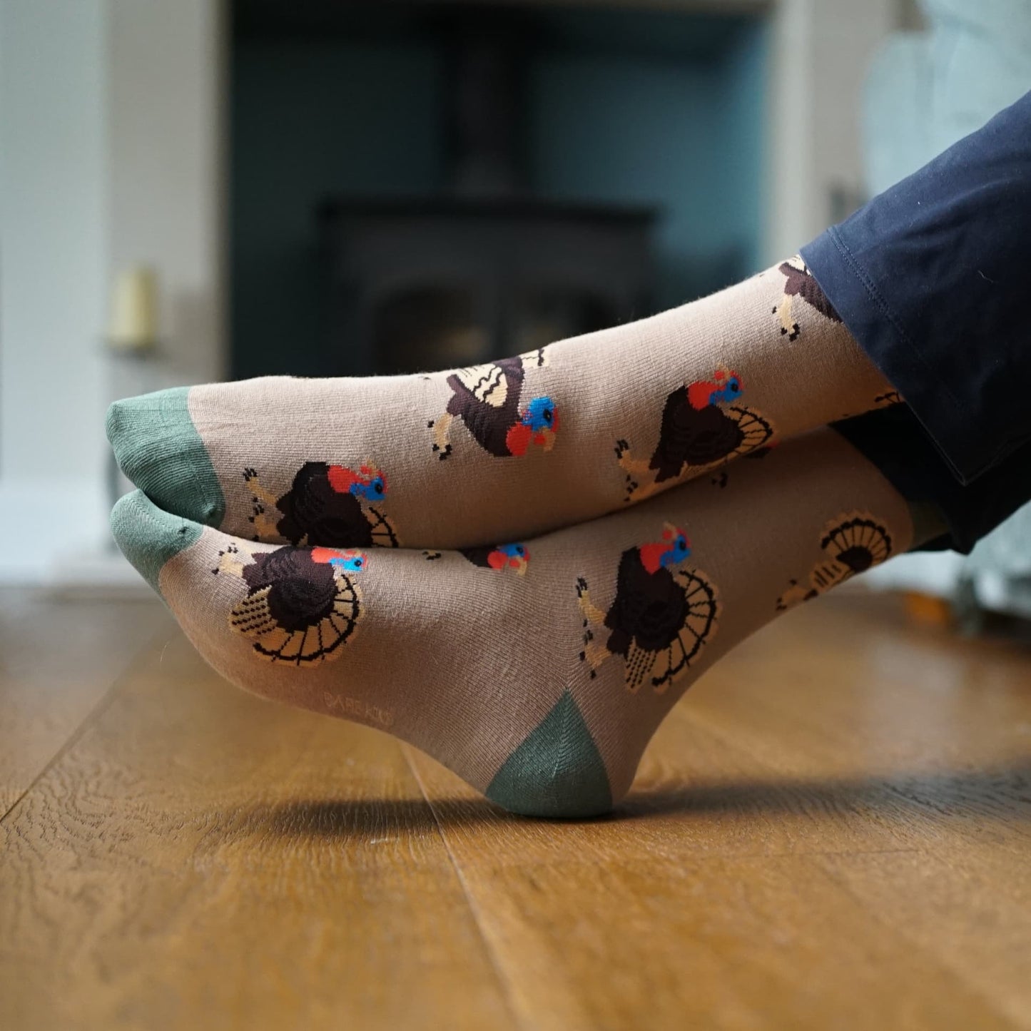 Person wearing socks with Turkey design sitting on a couch.