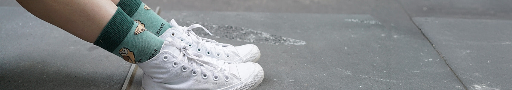 Green barn owl socks worn with white sneakers on a blurred background