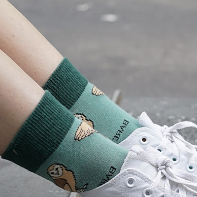 Green barn owl socks worn with white sneakers on a blurred background