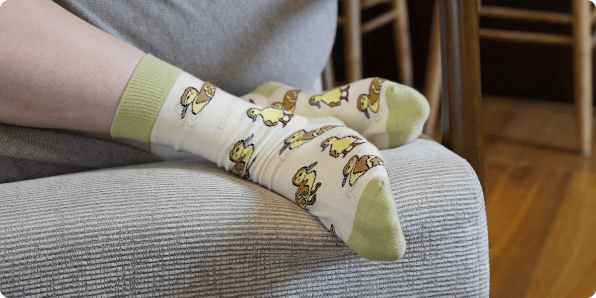 Person wearing ducklings bamboo socks on a chair