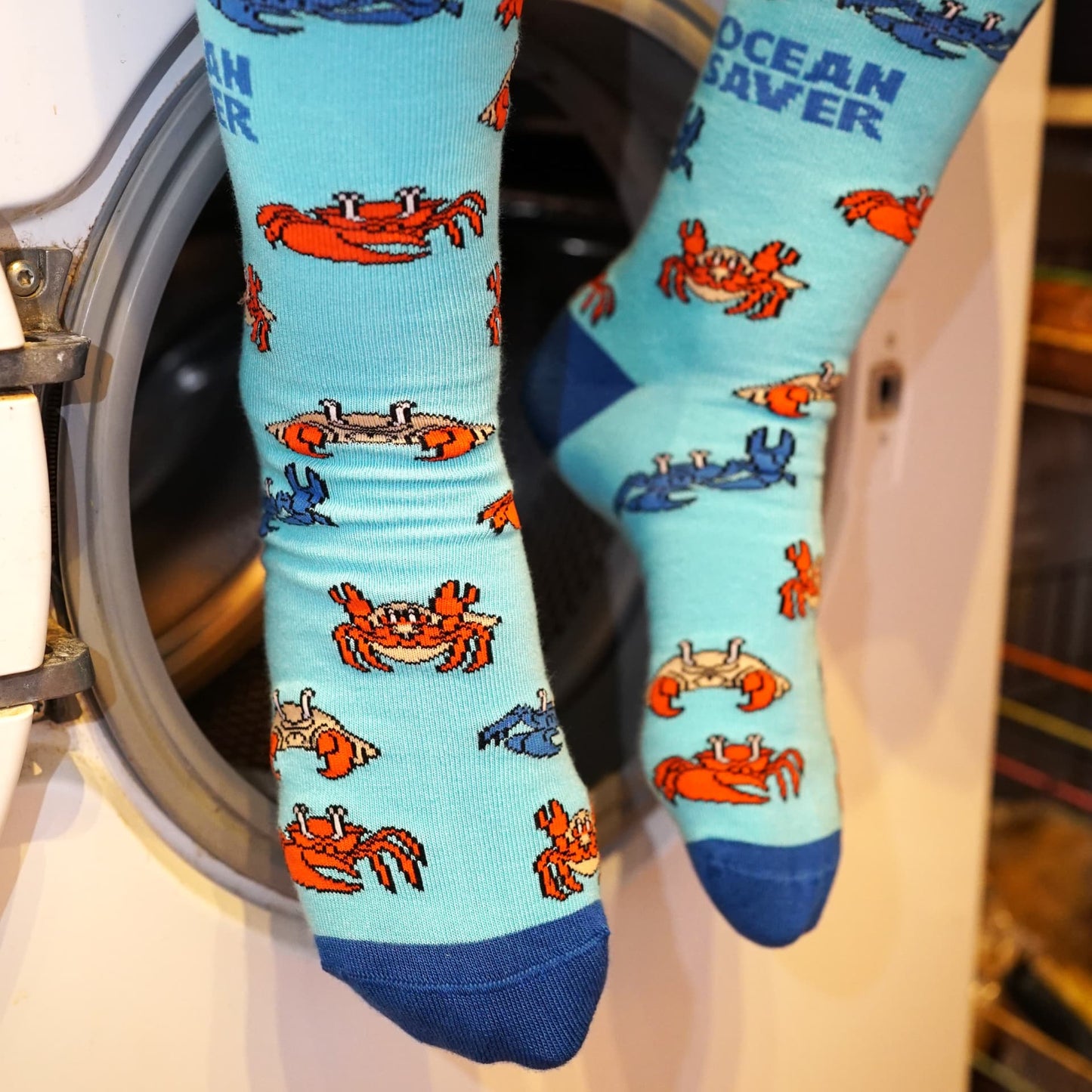 model sitting on washing machine and wearing blue ocean saver crab bamboo socks
