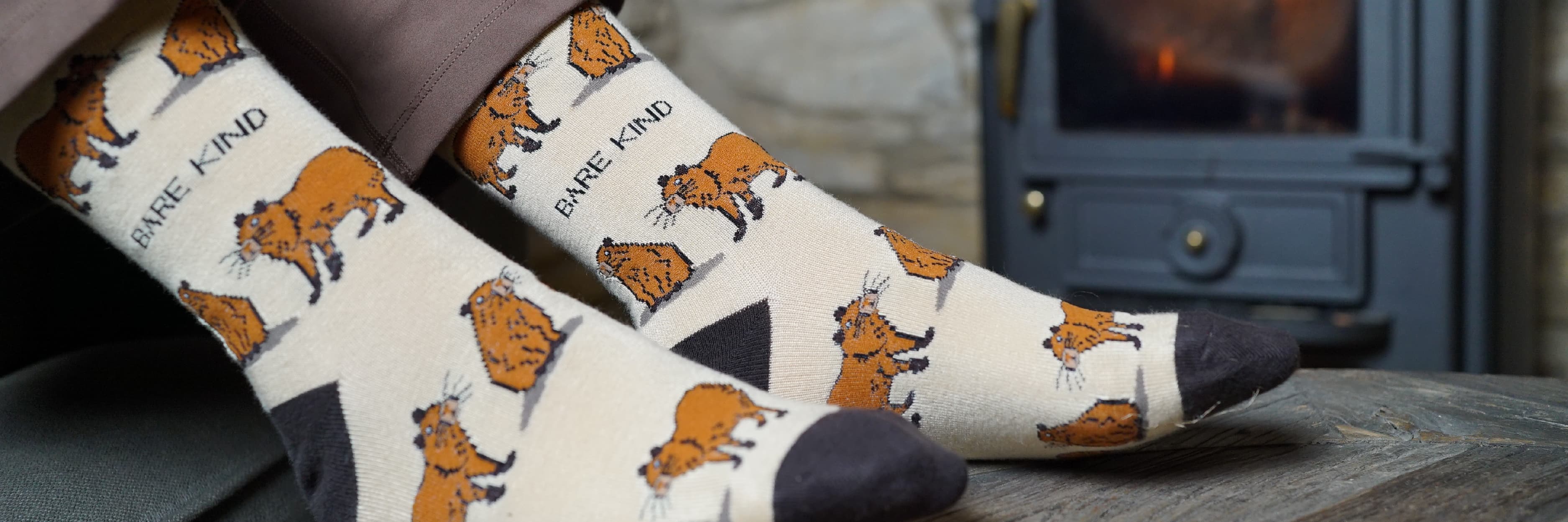 Pair of capybara bamboo socks on a surface with a fireplace in the background