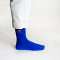 minimalist side view of standing model wearing ribbed blue bamboo socks with embroidered tiger motif on cuff