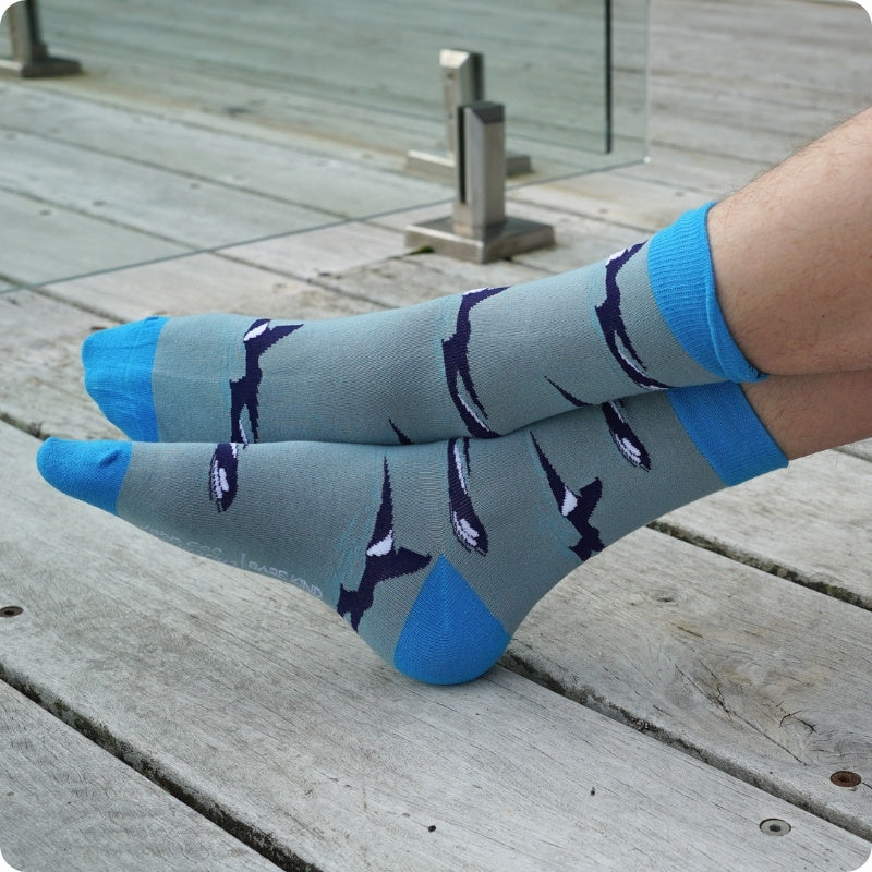 Light blue socks with orca design worn on a wooden deck
