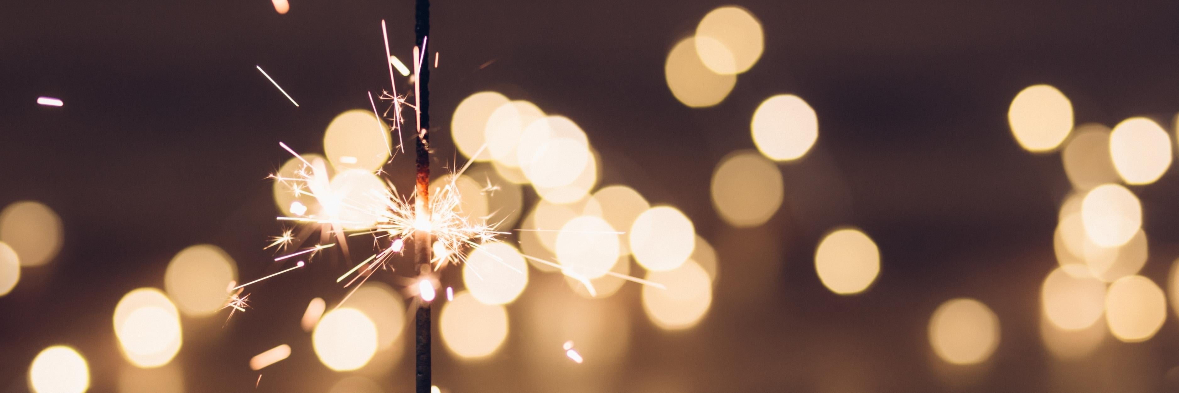 Sparkler emitting sparks against a blurred background of lights