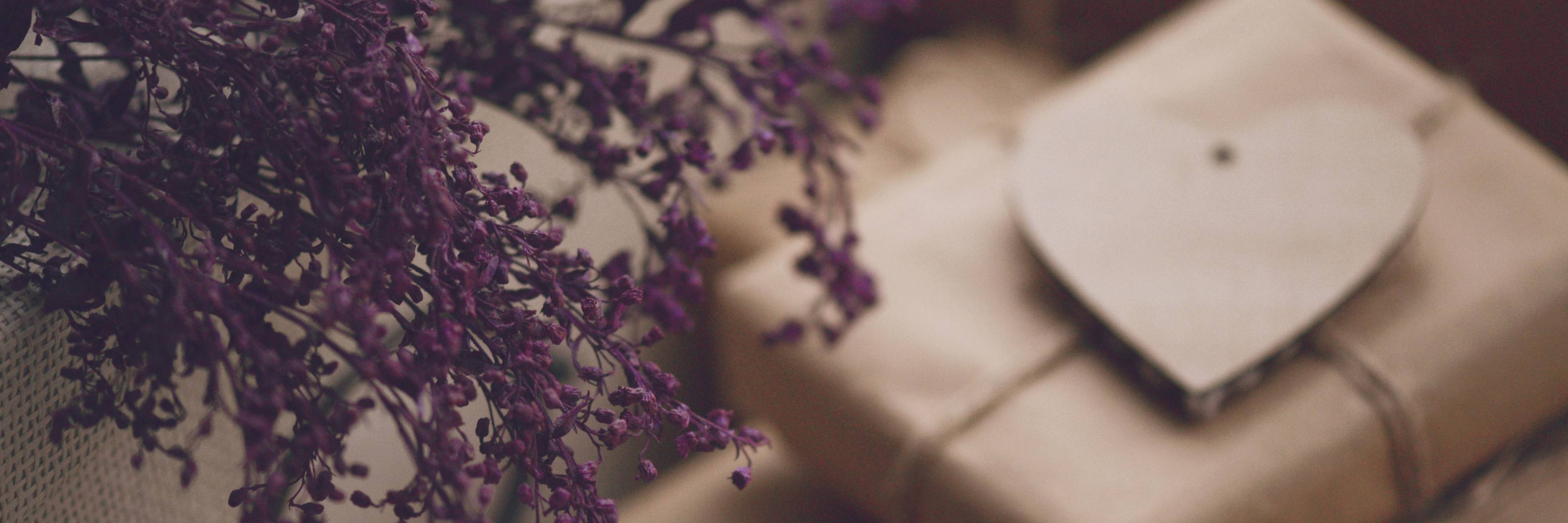 Close-up of a textured surface with a small heart-shaped object and purple flowers.