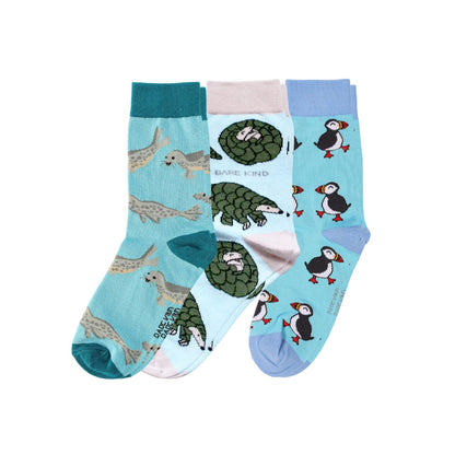 Three pairs of crew socks with animal prints, including puffin, pangolin, and seal, displayed against a plain white background.