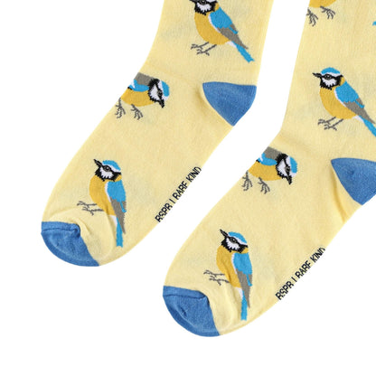 A pair of pale yellow crew socks with a repeating pattern of blue tits, bluebirds, and small birds, featuring blue heels and toes 
