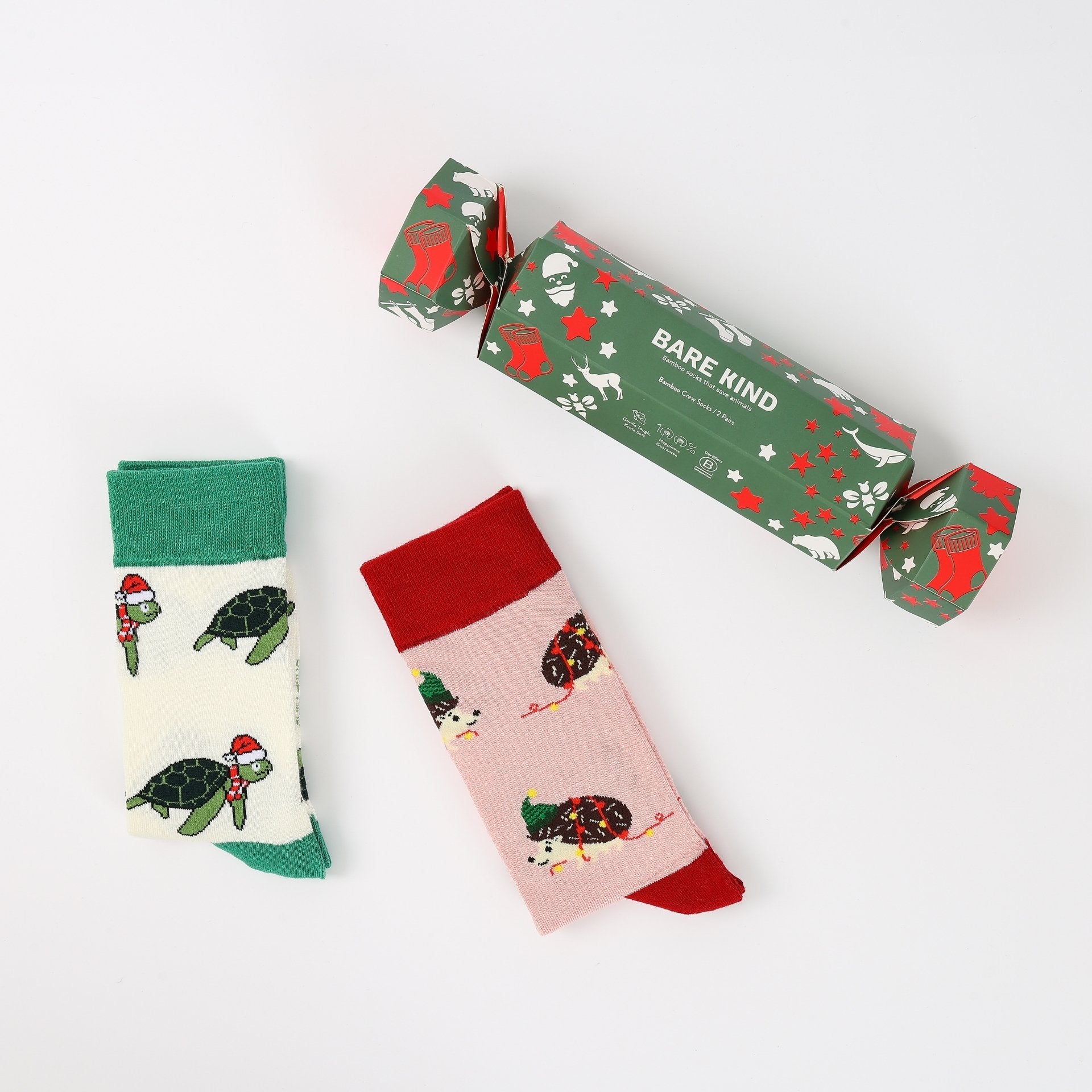 Two pairs of socks with festive designs and a branded box on a white background
