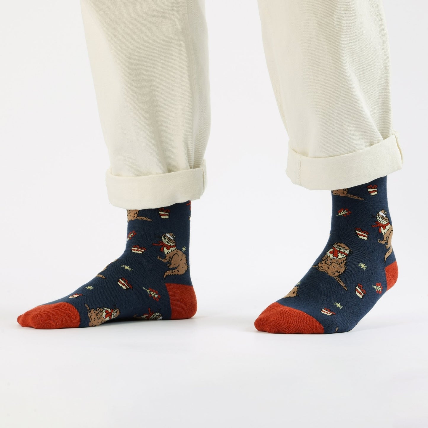 Blue Christmas Otter socks worn with white pants on a white background