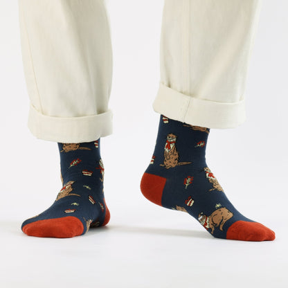 Blue Christmas Otter socks worn with white pants on a white background