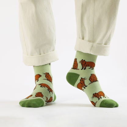 Green capybara bamboo sock worn by a person on a white background