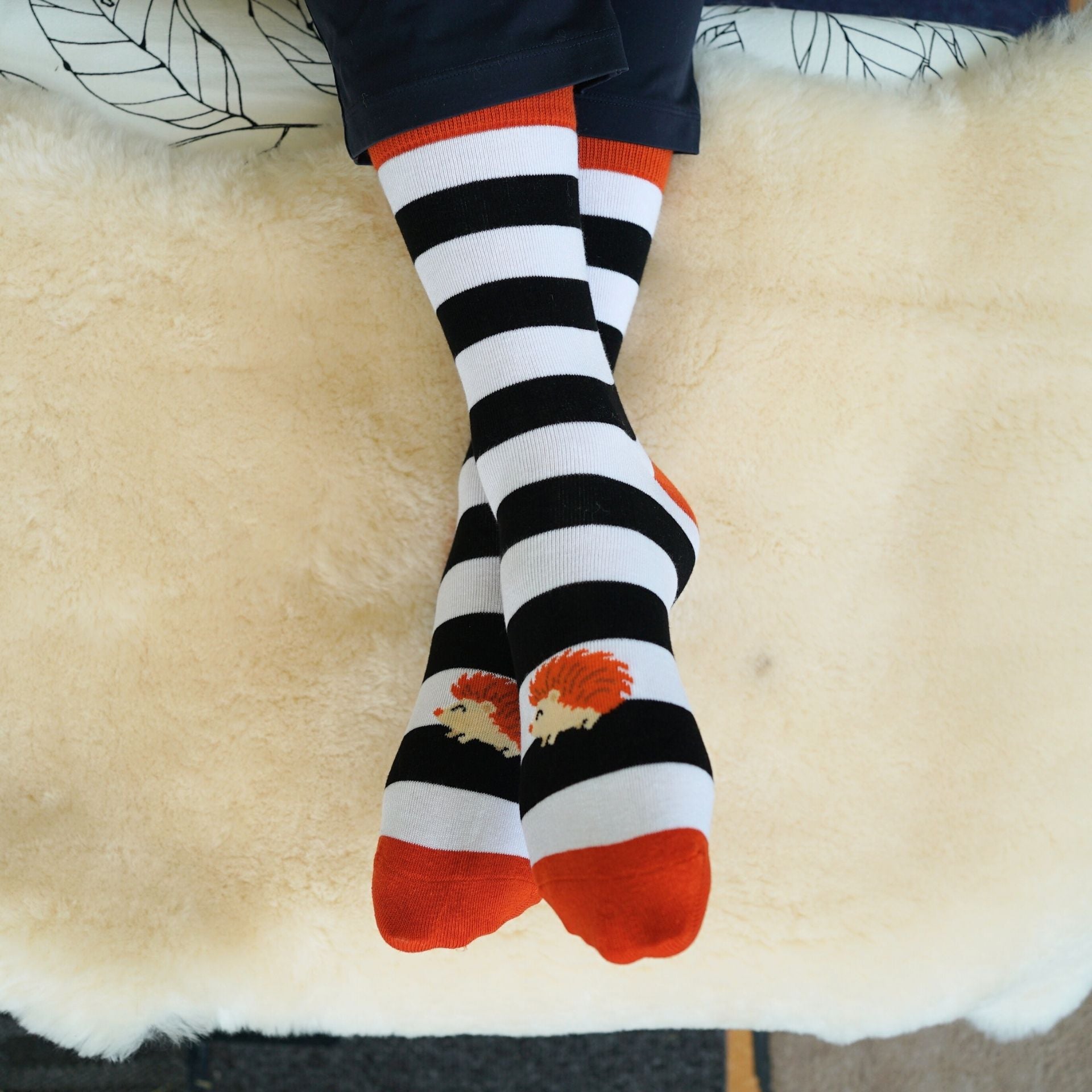 Black and white striped socks with rooster design on a fluffy beige surface