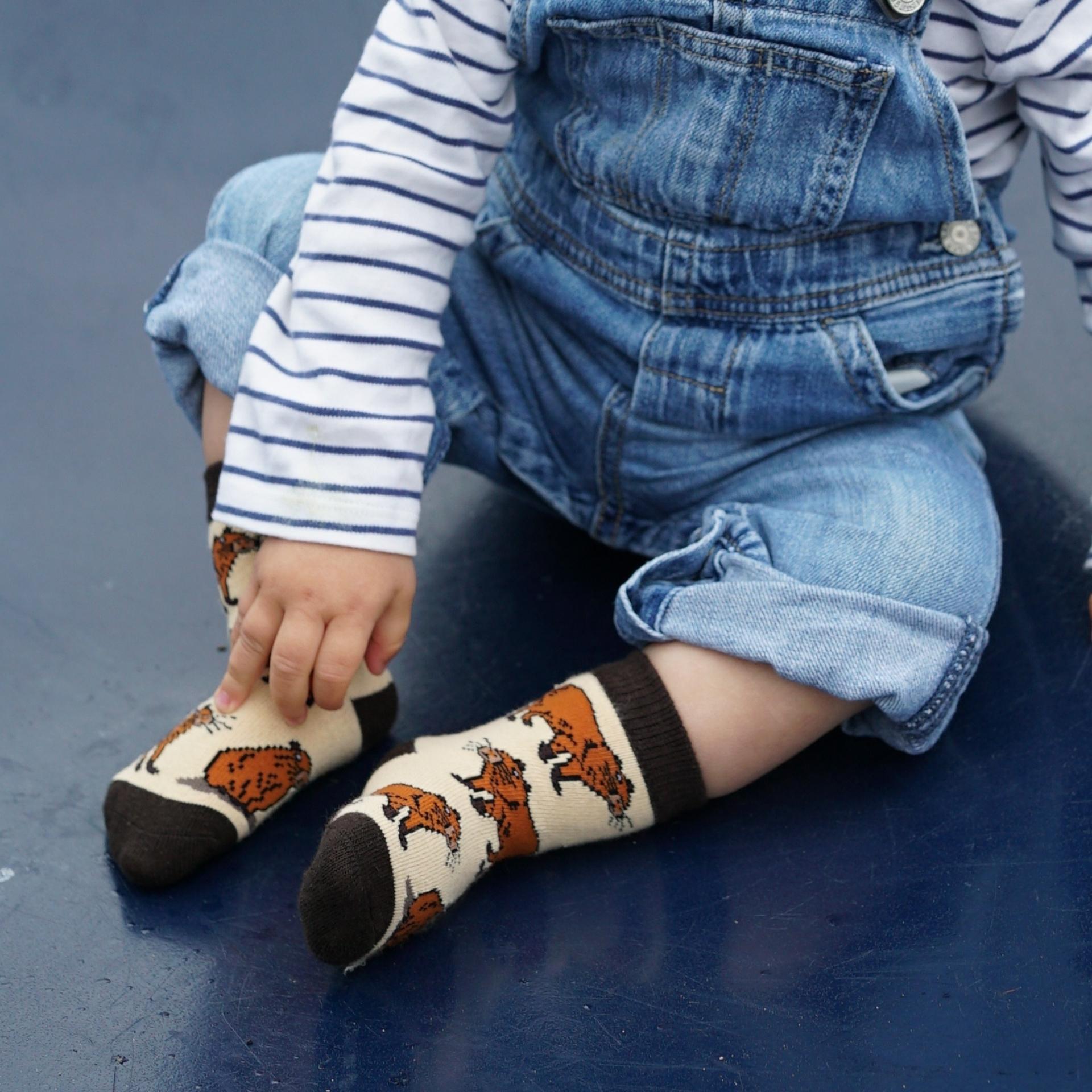 Child wearing capybara-patterned socks on a blue surface