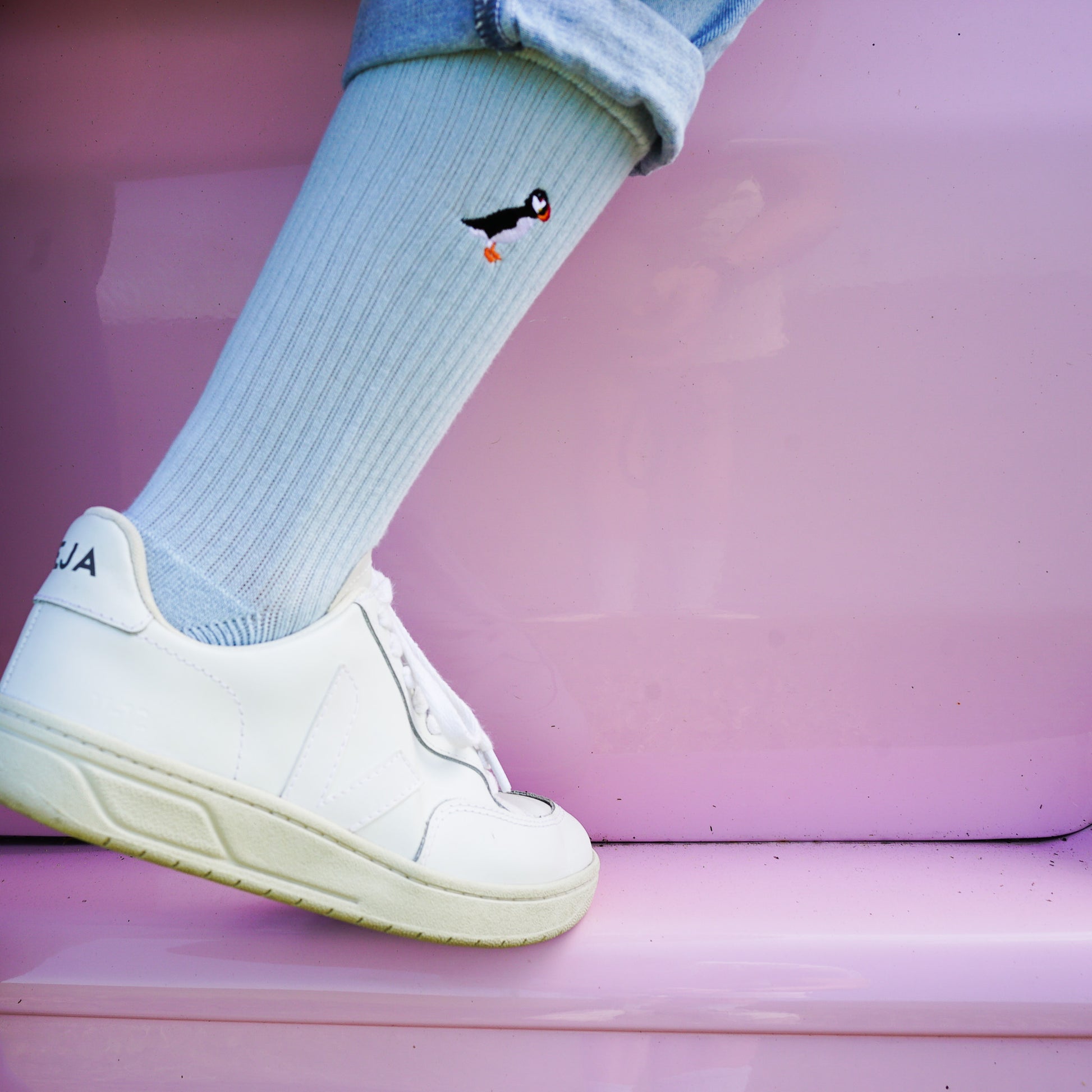 Model wearing pastel blue socks with penguin small motif design embroidered on cuff