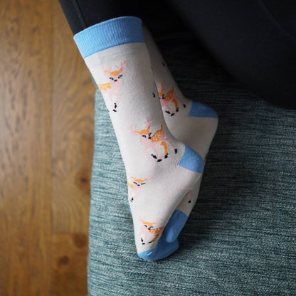 Person wearing deer socks sitting on a couch with wooden floor.