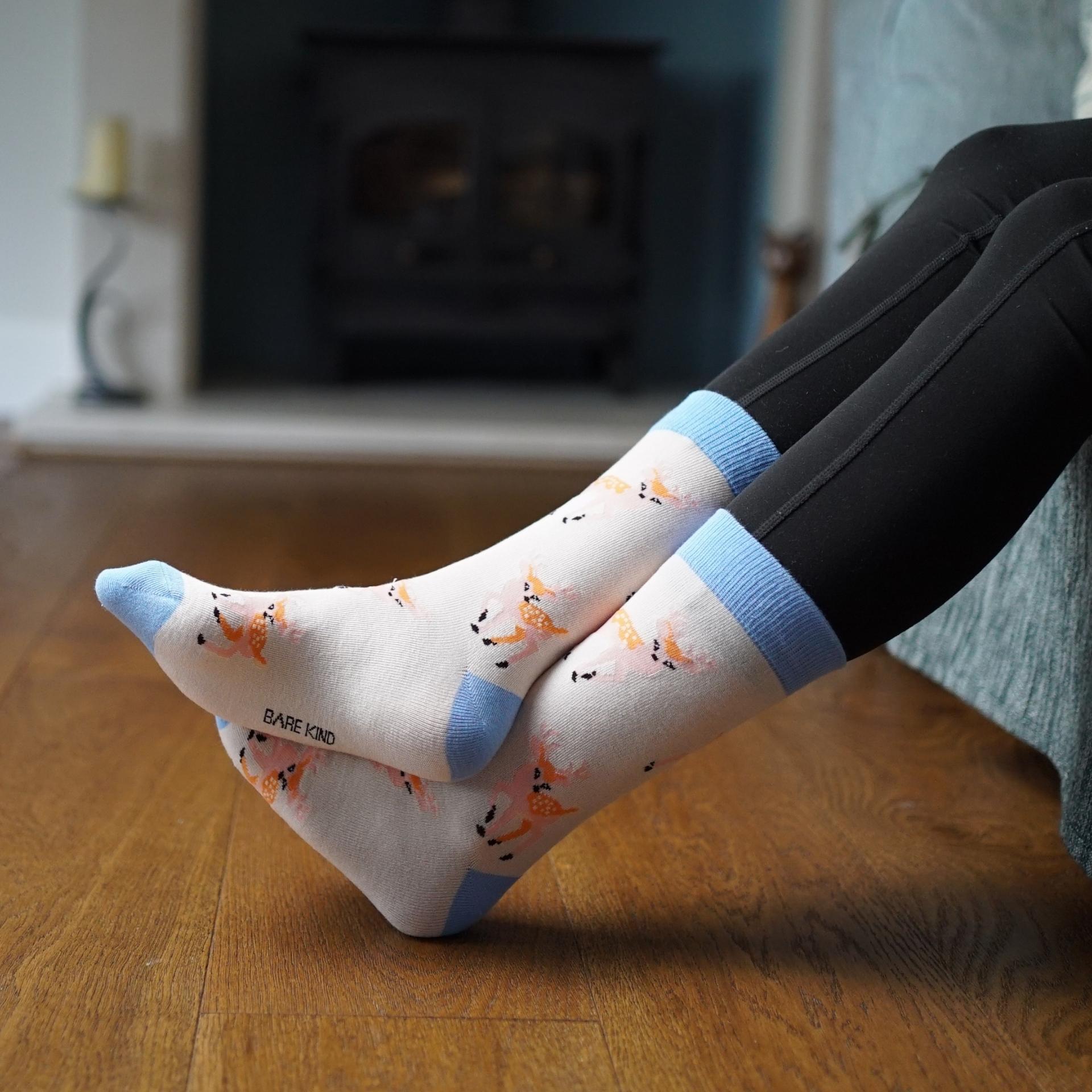 Person wearing deer socks sitting on a couch with wooden floor.