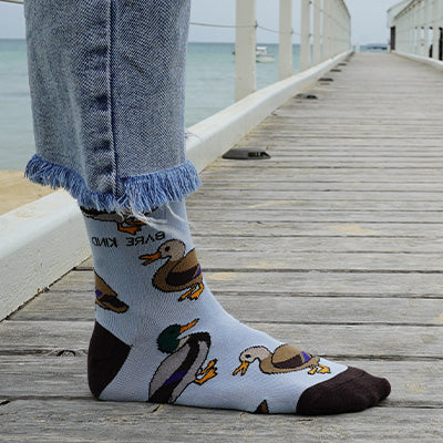 Person wearing socks with duck design on a wooden dock