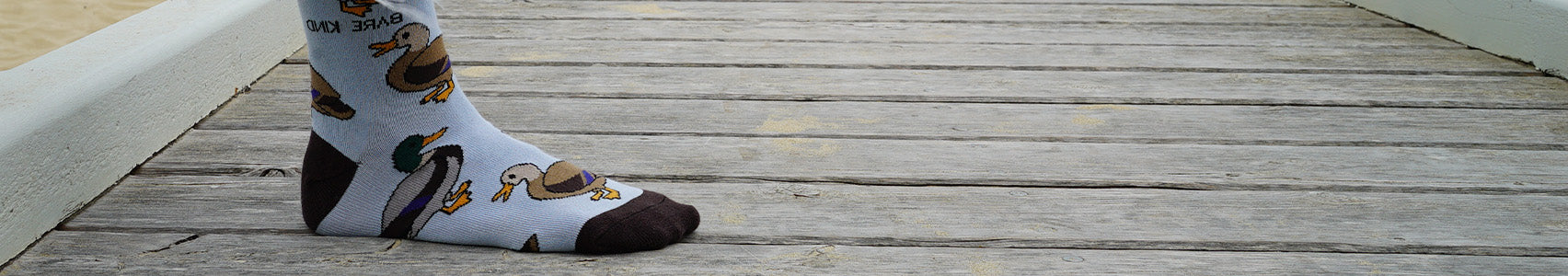 Person wearing socks with duck design on a wooden dock