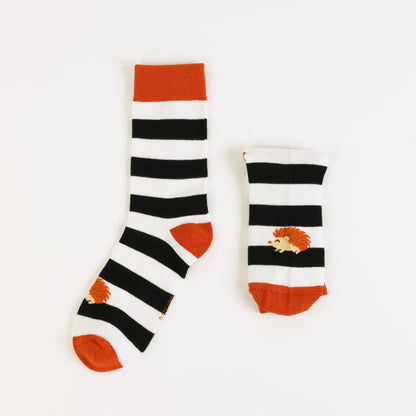 Pair of black and white striped socks with orange accents on a white background