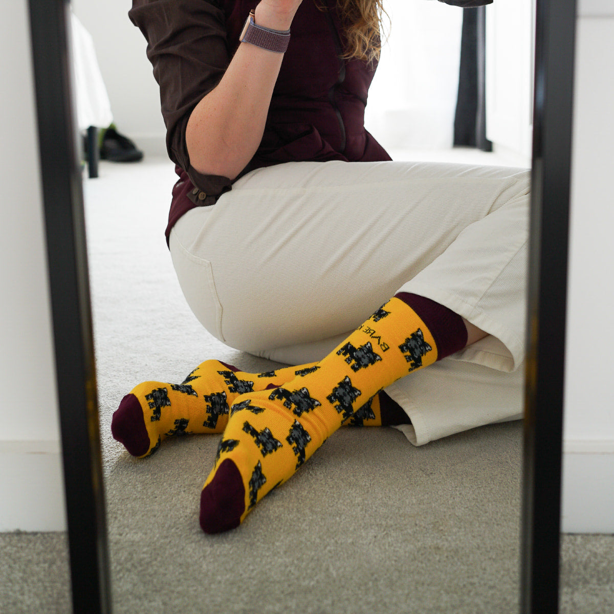 Model wearing highland dog bamboo socks in front of mirror