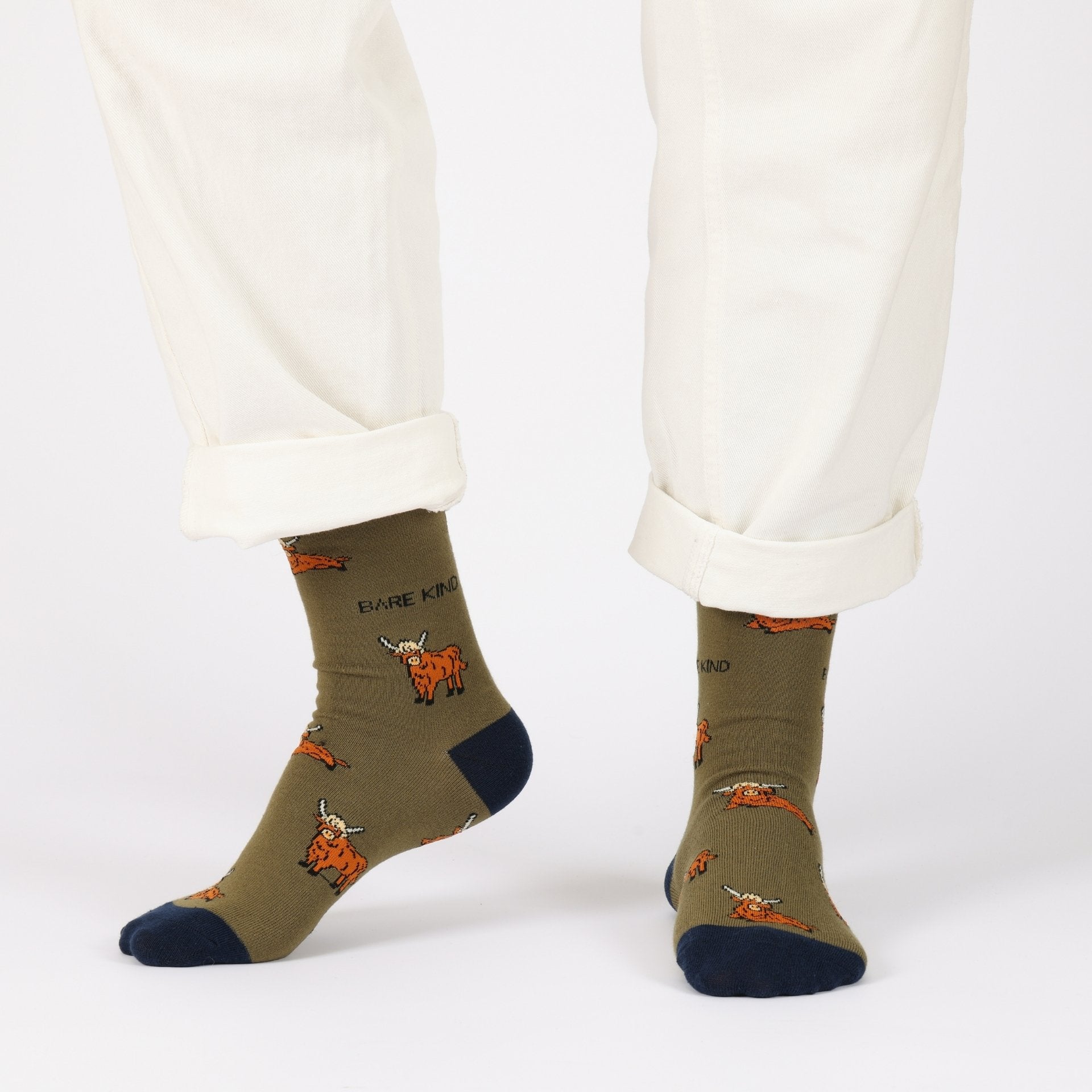 model with white trousers wearing green highland cow bamboo socks