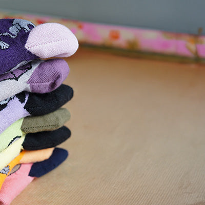 Stack of colorful socks on a wooden surface with a blurred background