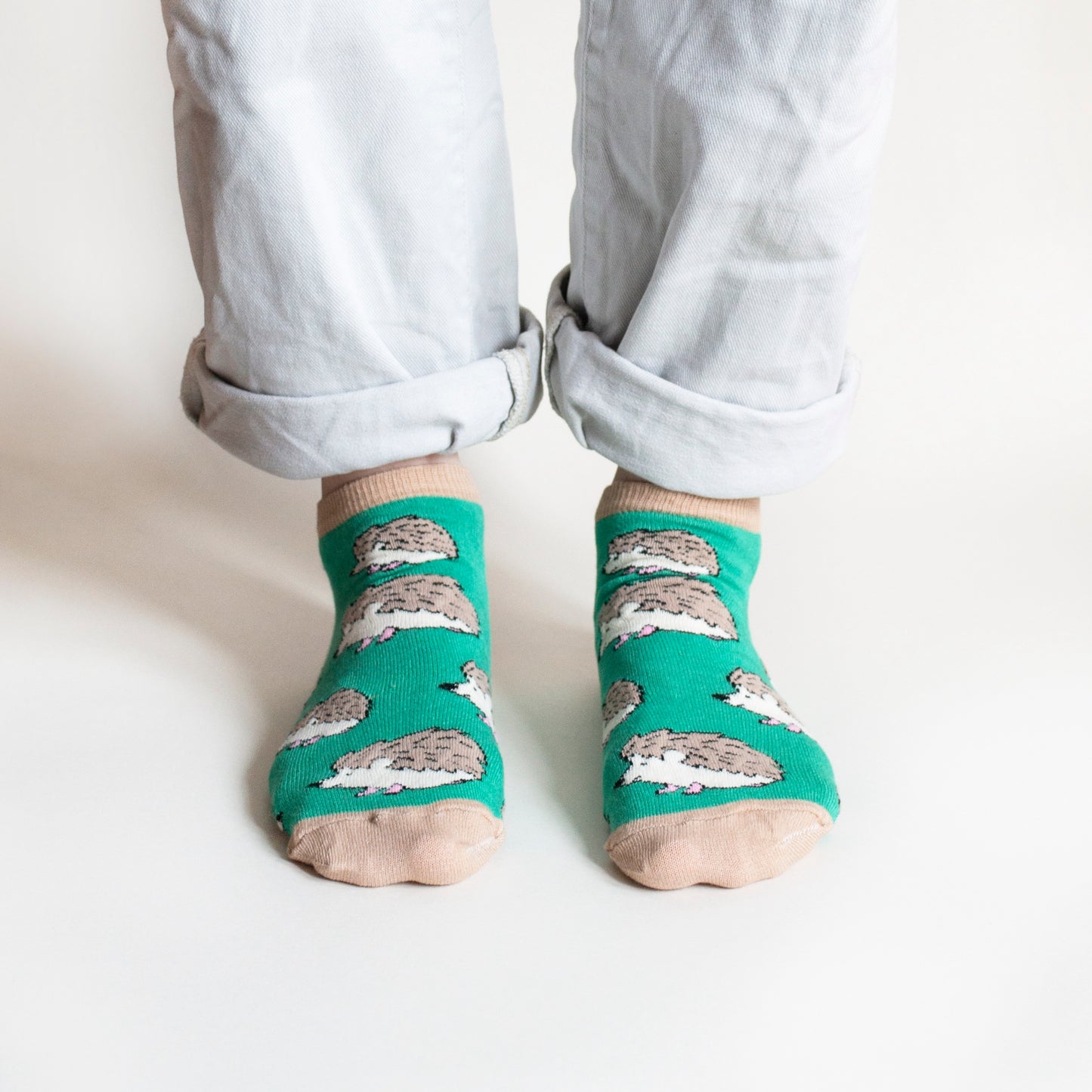 standing model wearing bamboo trainer socks in green hedgehog design