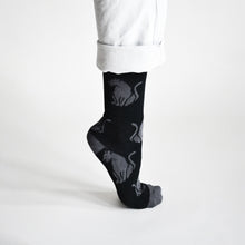side profile view of standing model, on tip toes, wearing soft top black panther bamboo socks