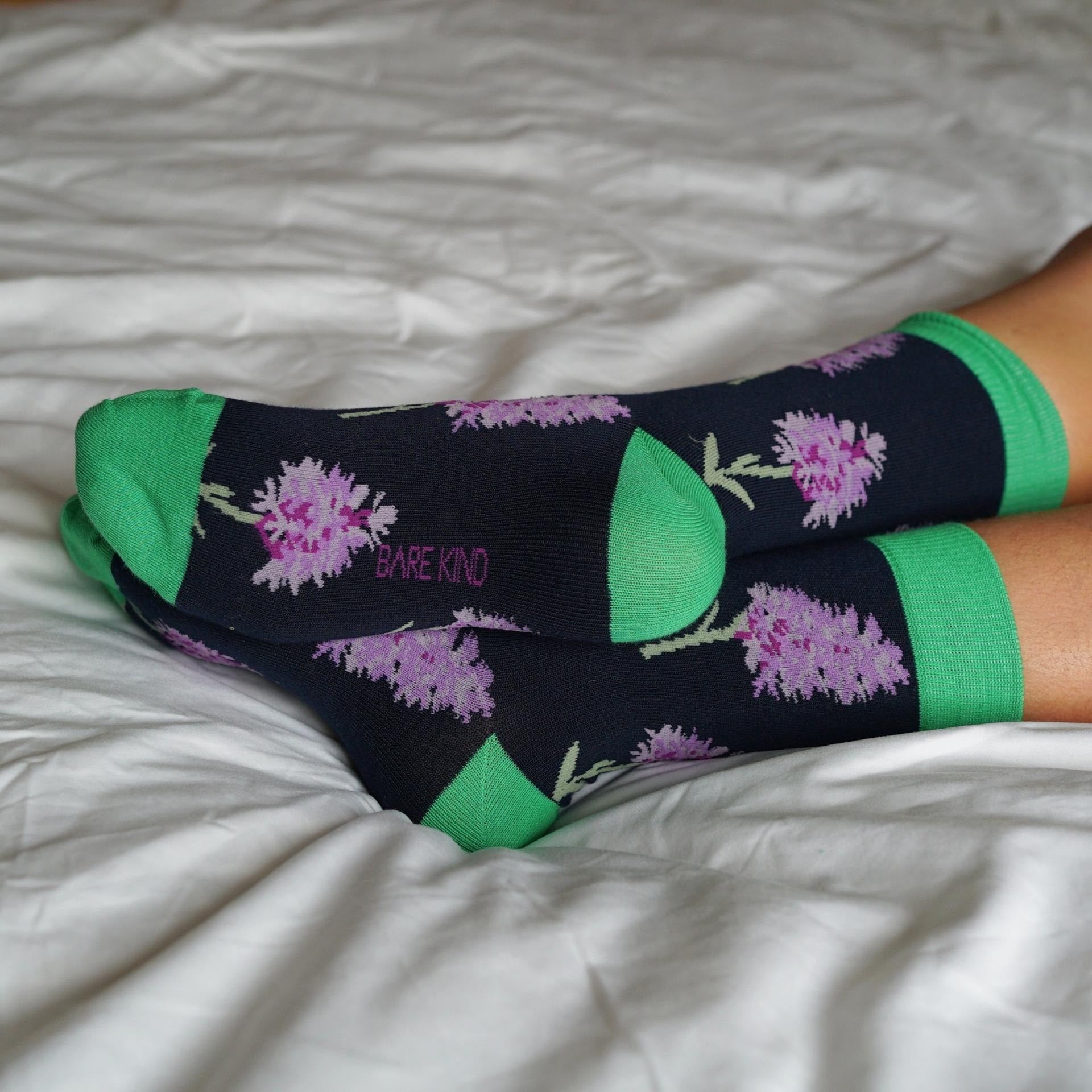 Orchid socks with green accents on a white bedspread