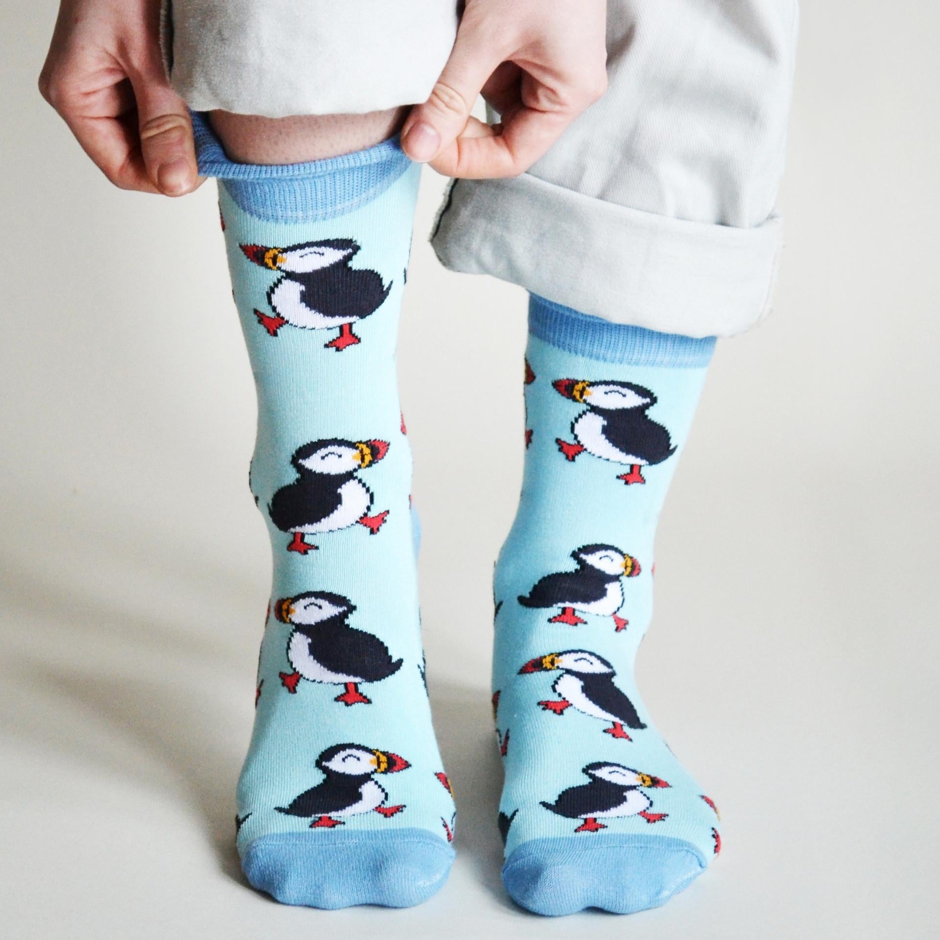 Light blue socks with puffin design worn by a person on a plain background
