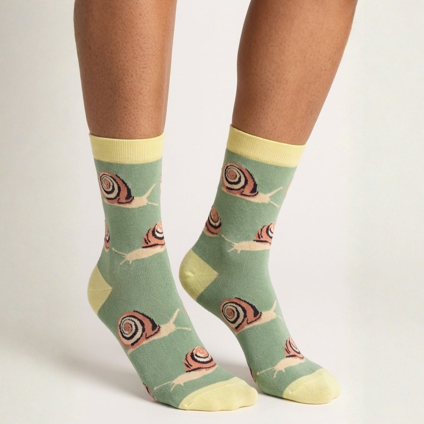 Green socks with snail pattern worn by a person on a white background