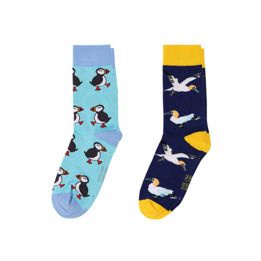 Two novelty crew socks shown flat against a white background. The left sock is light blue with puffin illustrations, and the right sock is dark navy with gannet illustrations and yellow accents.