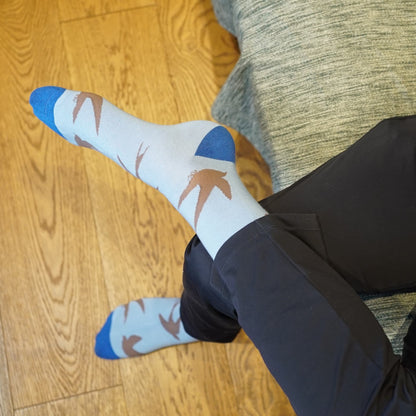 Person wearing swift socks sitting on a couch with wooden floor.
