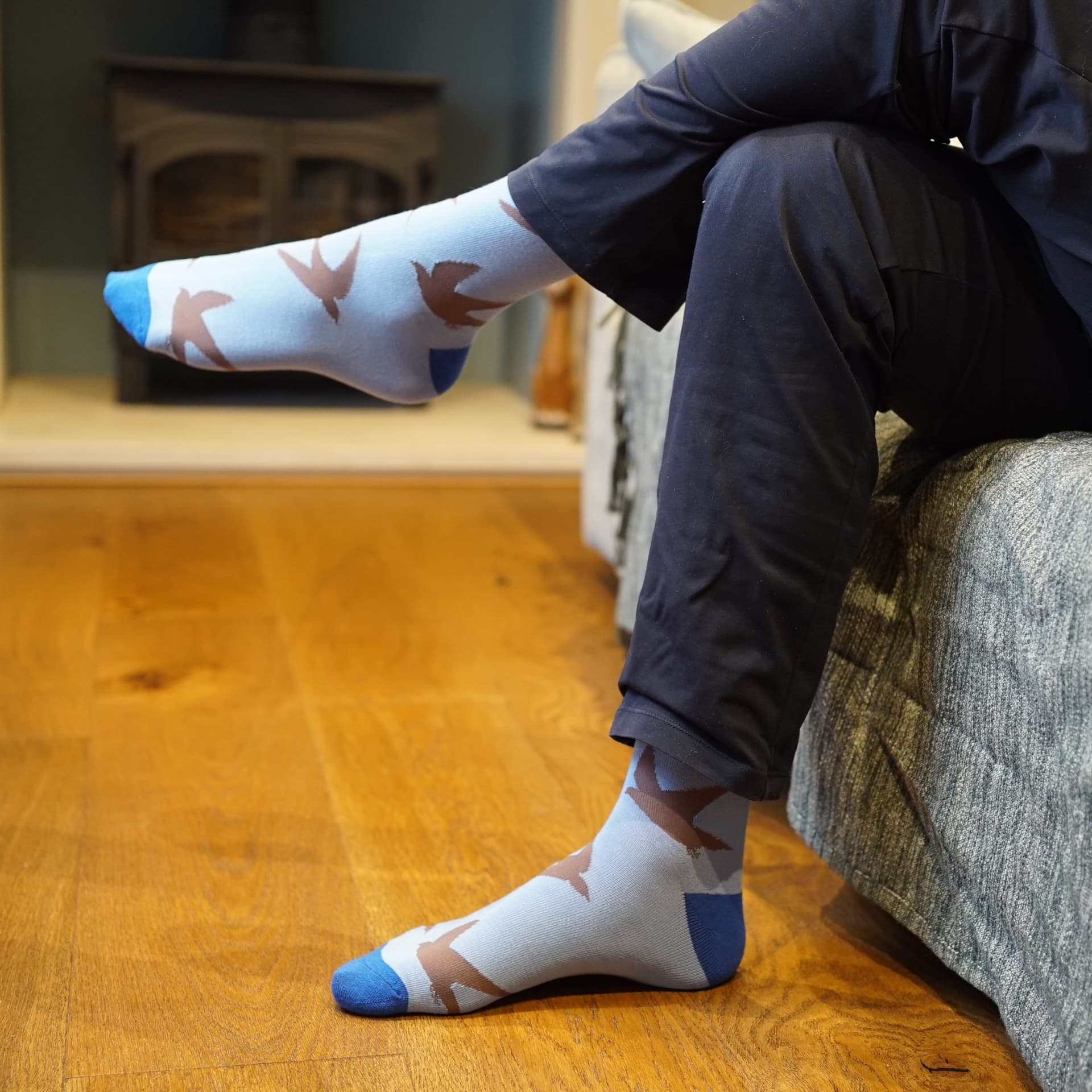 Person wearing swift socks sitting on a couch with wooden floor.