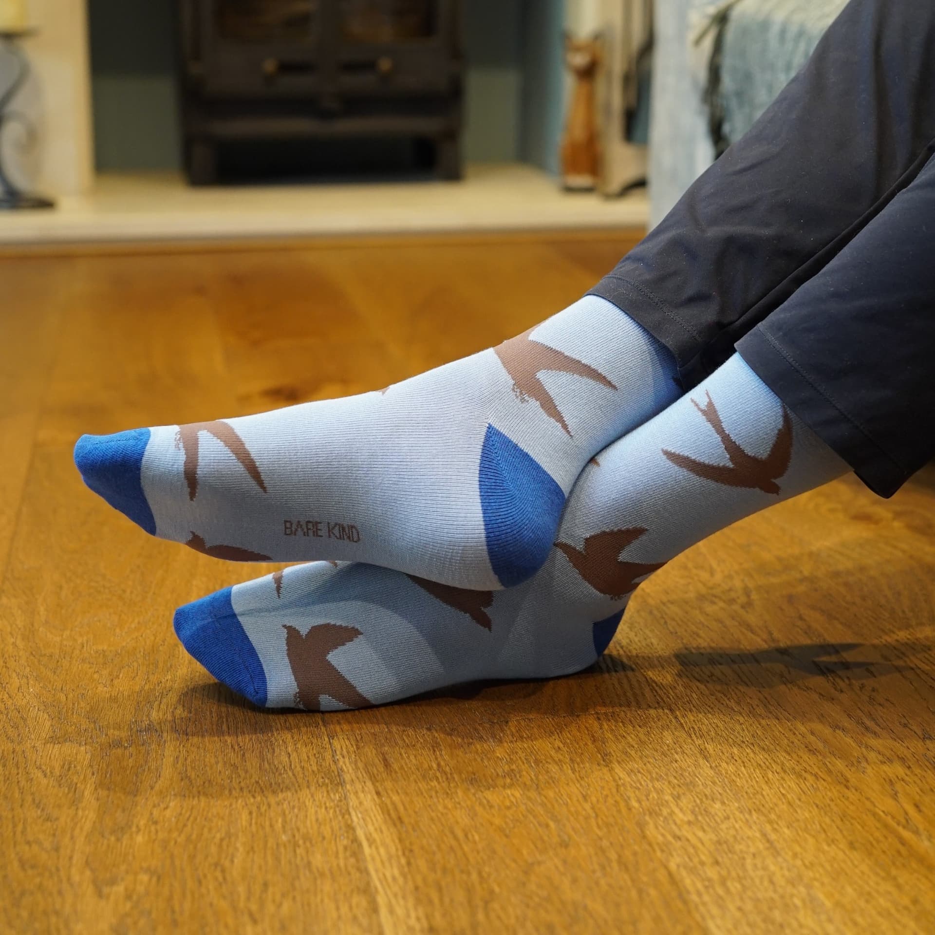 Person wearing swift socks sitting on a couch with wooden floor.