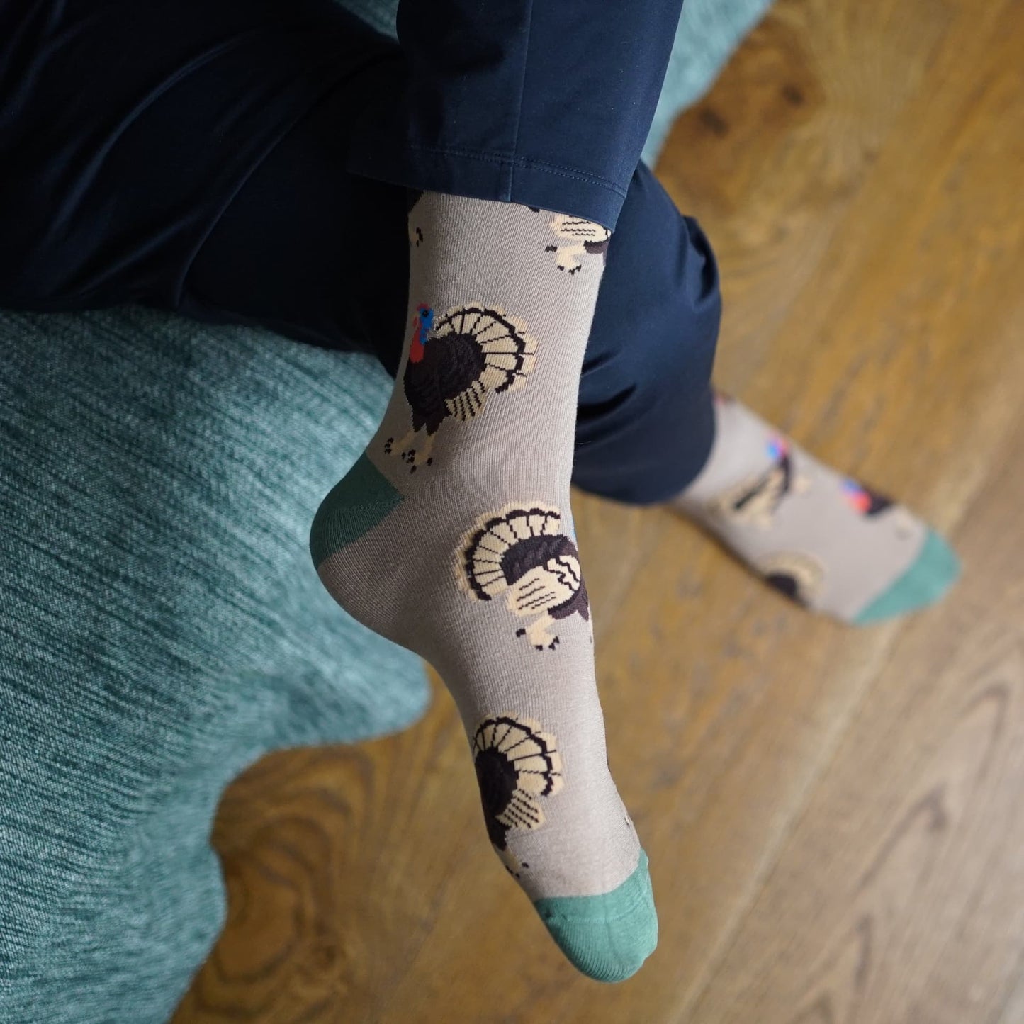 Person wearing socks with Turkey design sitting on a couch.