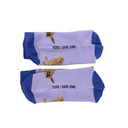 A pair of low-cut socks with a light lavender purple body, dark blue heels and toes, and a cartoon graphic of a yellow bird with the text 'RSPB I BARE KIND' printed on the side.