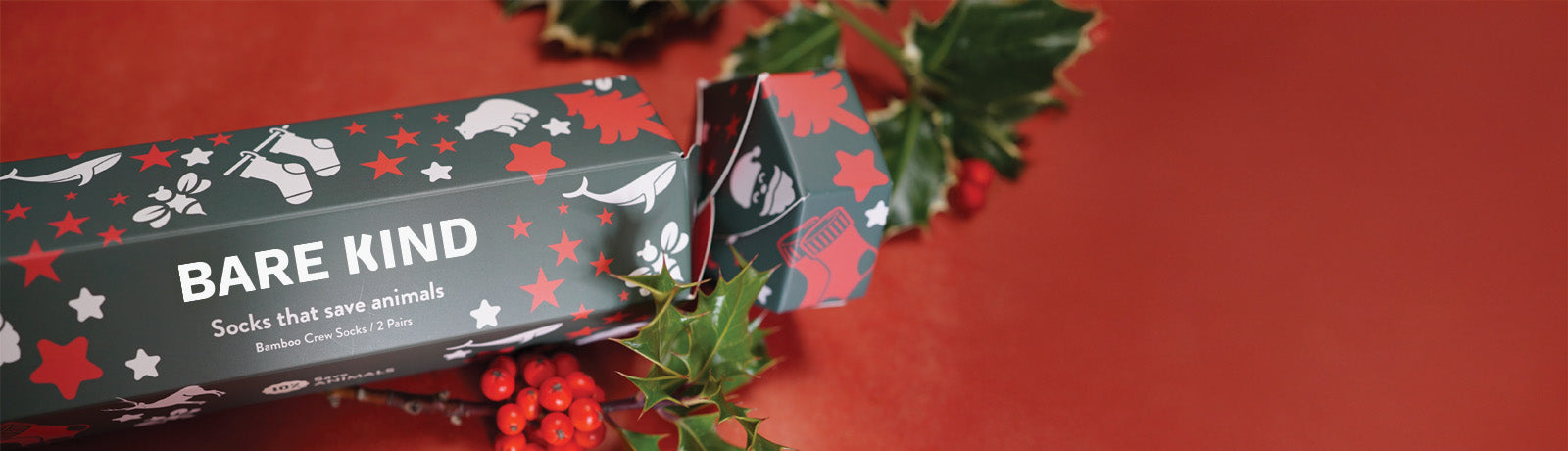Bare Kind sock packaging with holly leaves on a red background