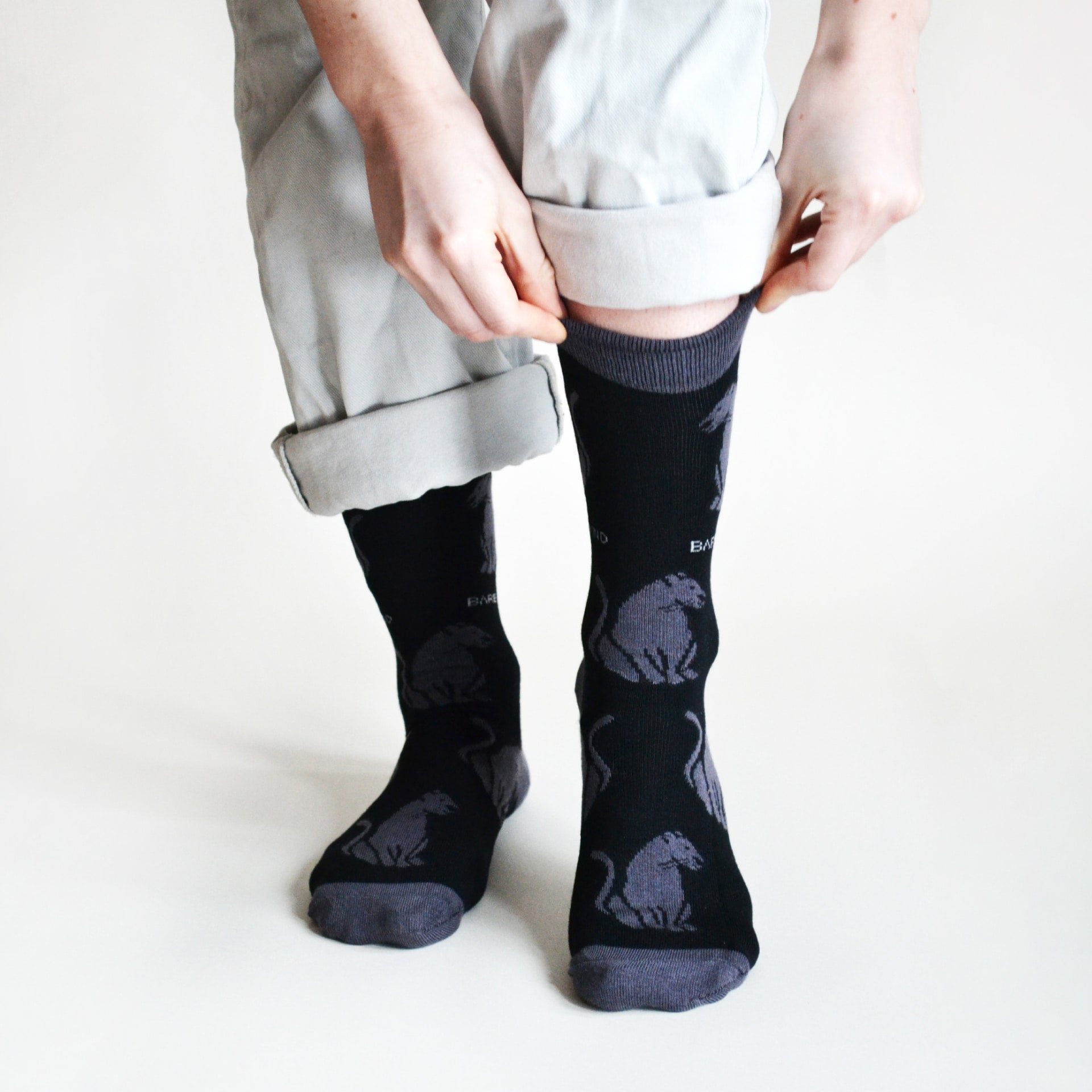 front view of model wearing black panther bamboo socks and pulling the left cuff up