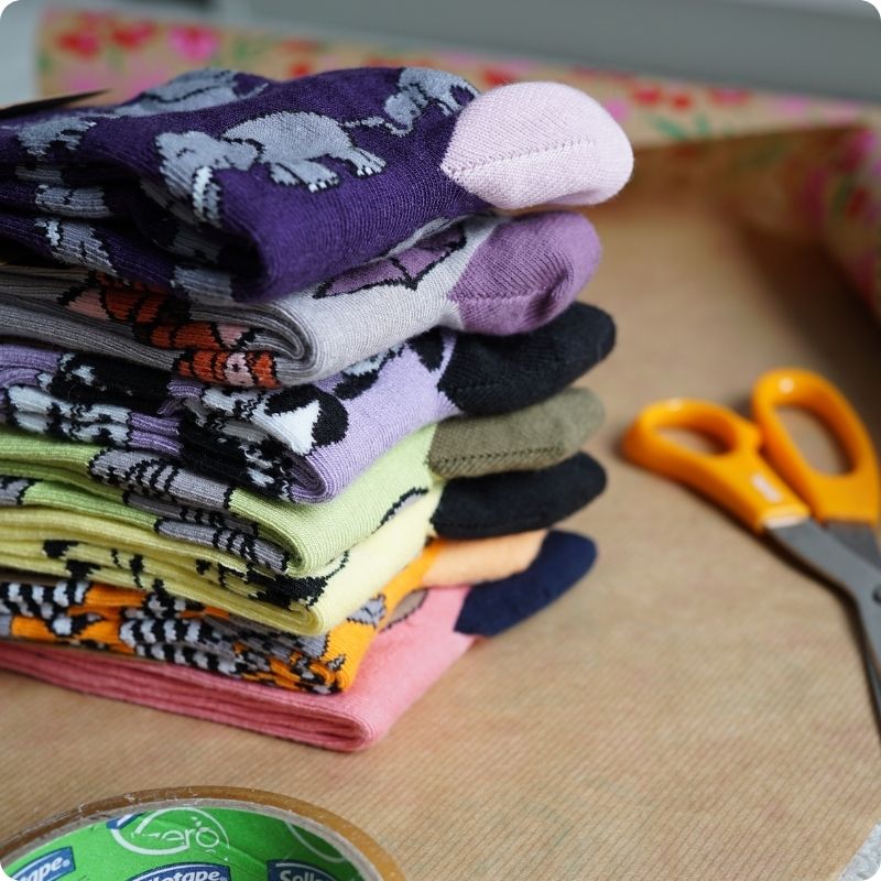 Stack of colorful socks with a pair of scissors on a wooden surface