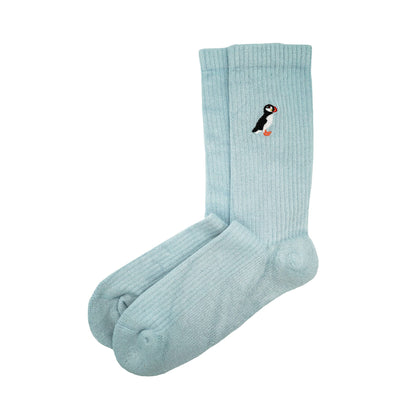 Minimalist flat lay picture of blue ribbed bamboo socks with puffin embroidered design on cuff