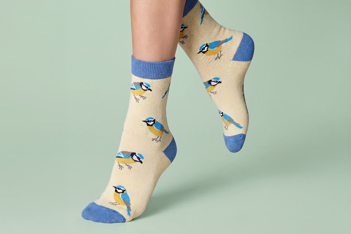 Beige socks with blue bird pattern worn by a person on a light green background