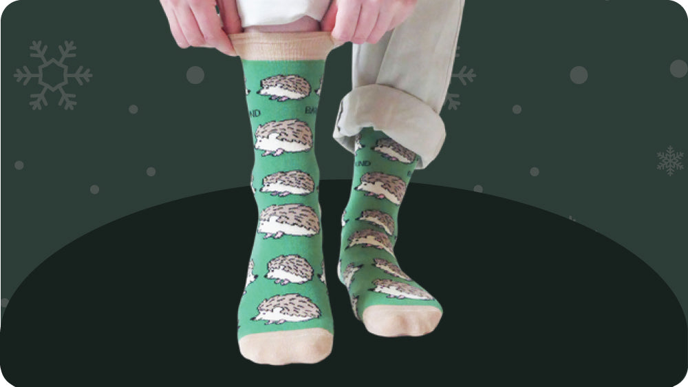 Green socks with hedgehog pattern worn by a person on a dark background