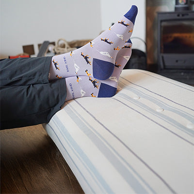 Person wearing socks with dog pattern lying on a bed