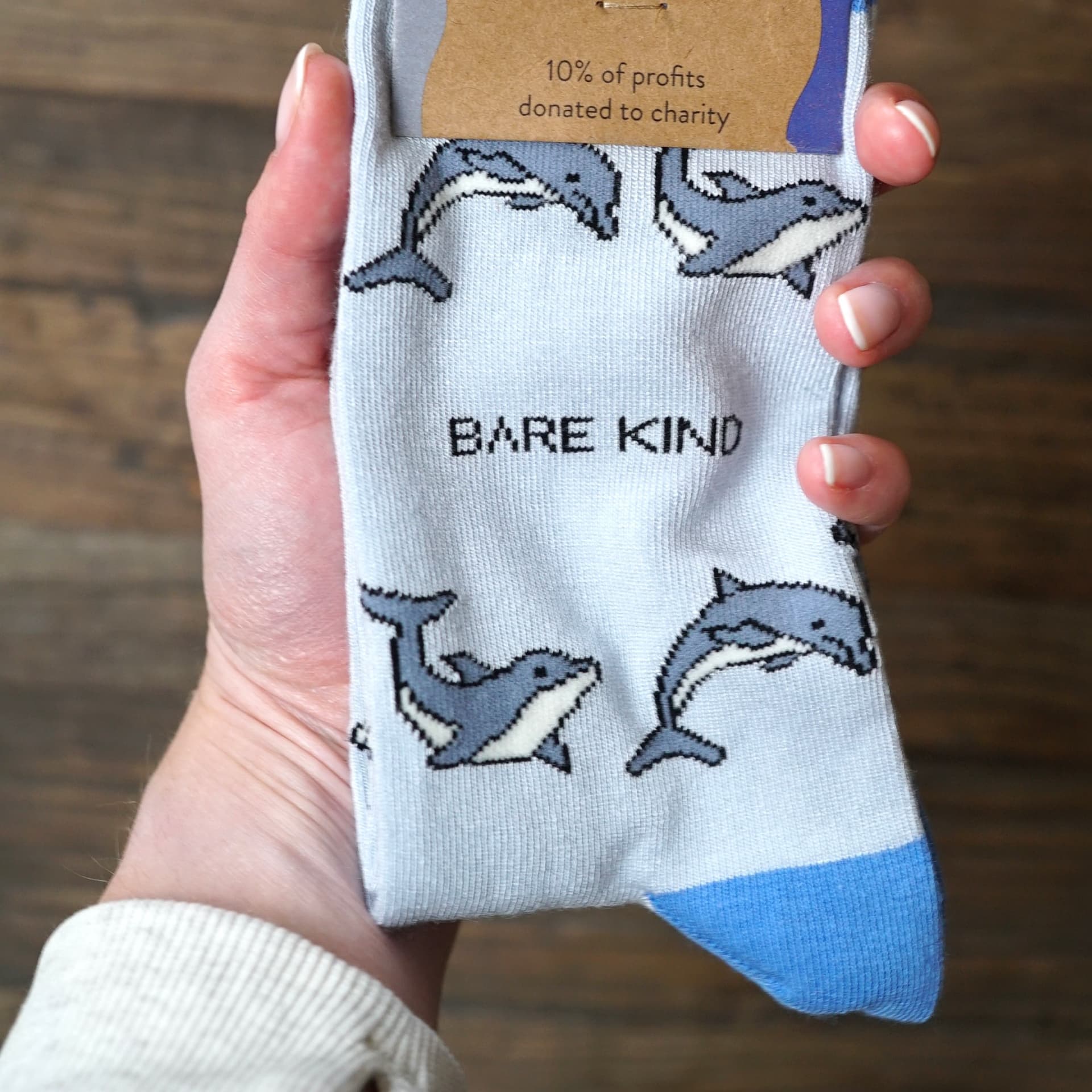 model holding the packaging of blue dolphin bamboo socks in her hand